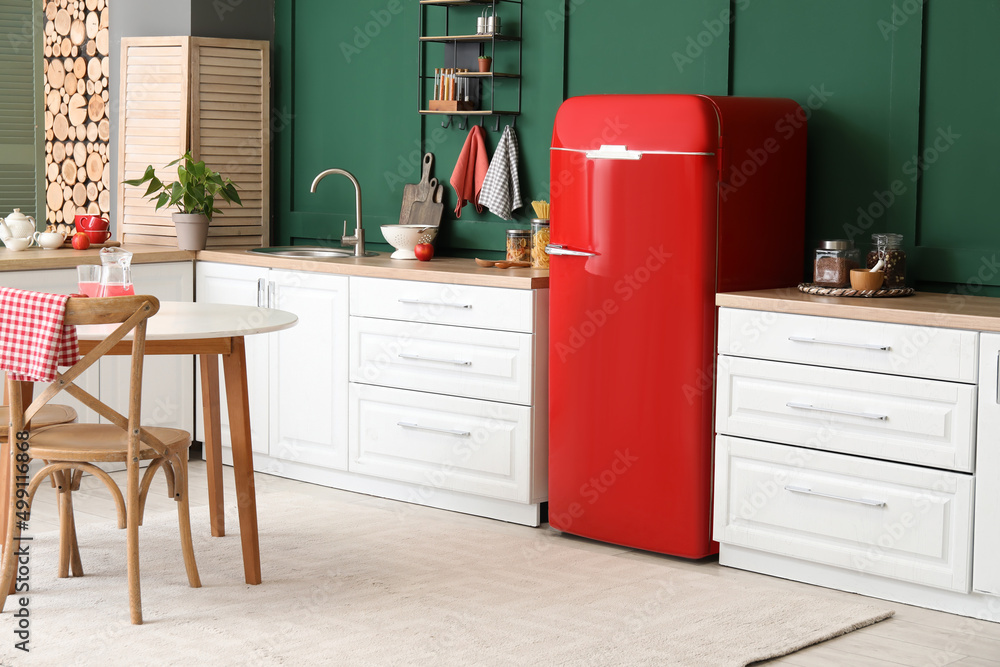 Interior of modern kitchen with dining table, stylish refrigerator and counters