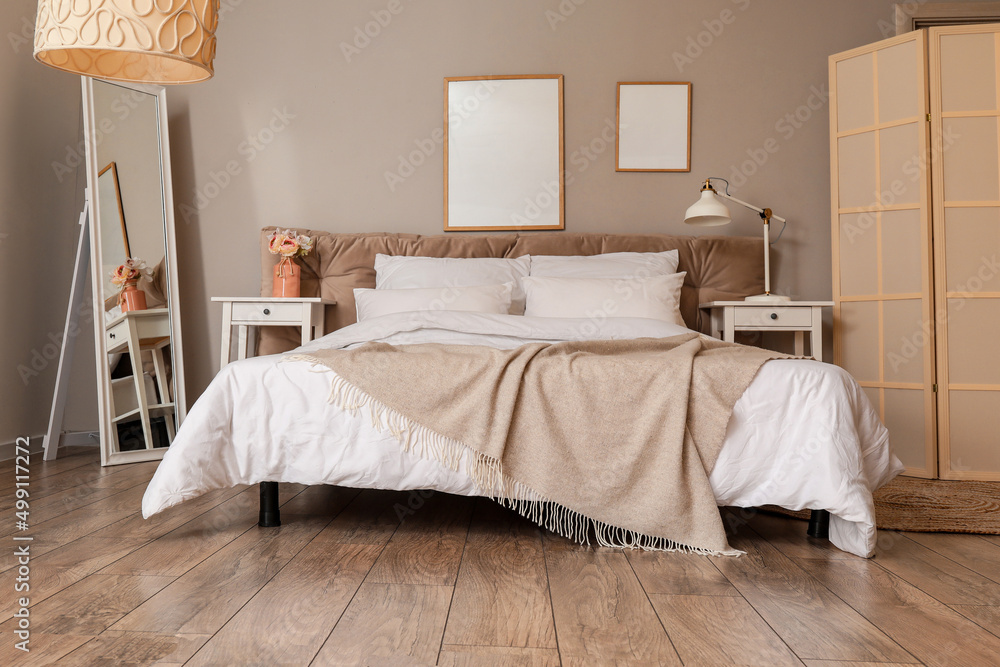 Interior of stylish bedroom with mirror and blank posters