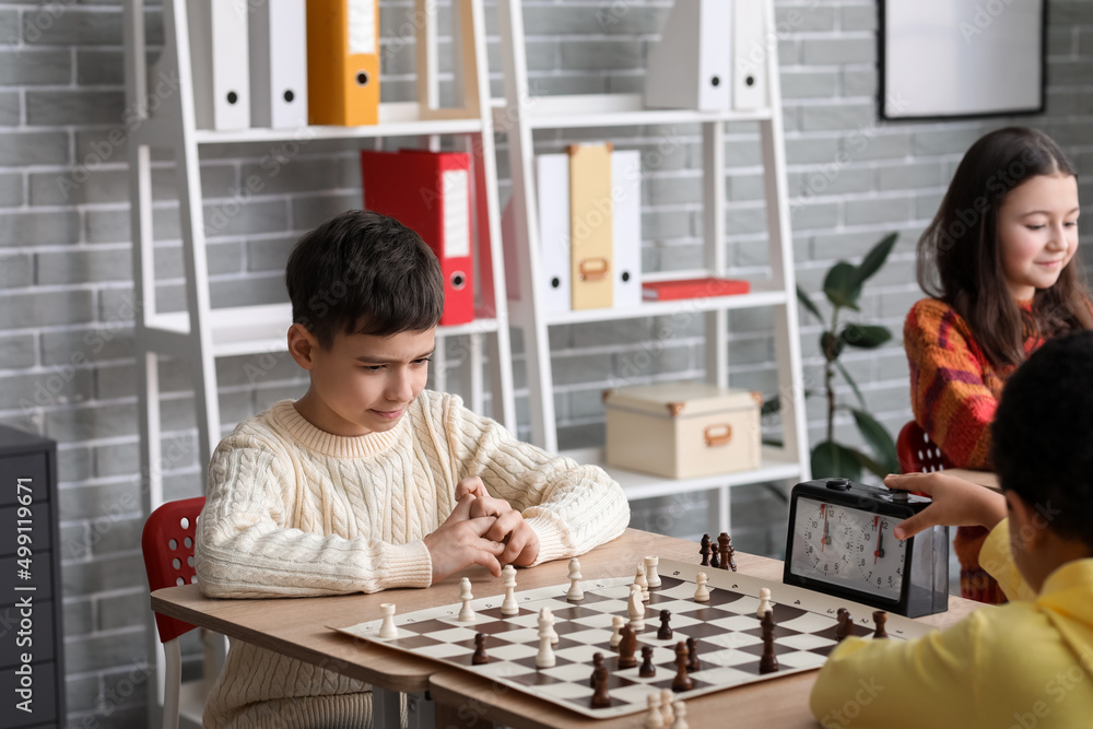 Little children playing chess during tournament in club