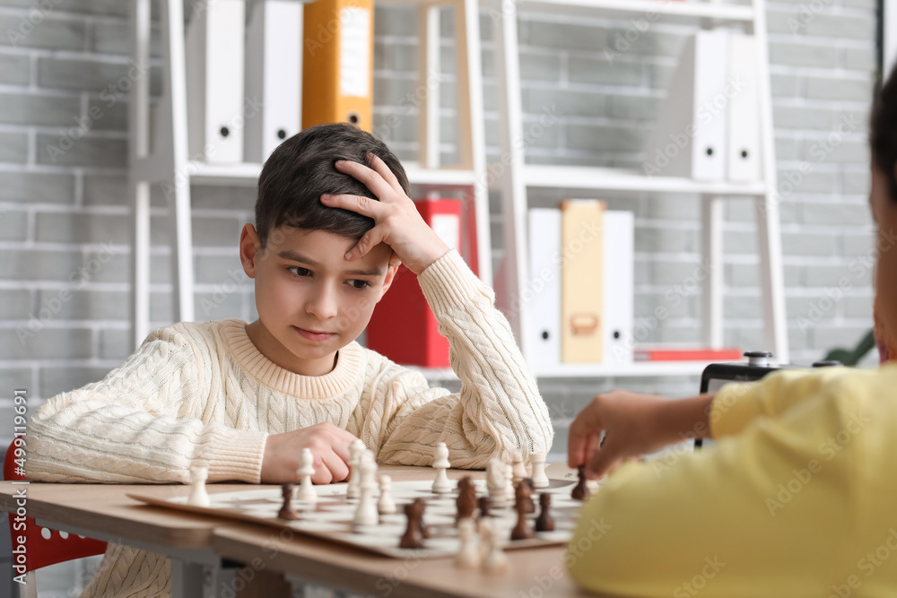 Little children playing chess during tournament in club