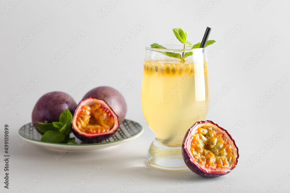 Glass of delicious passion fruit juice on light background