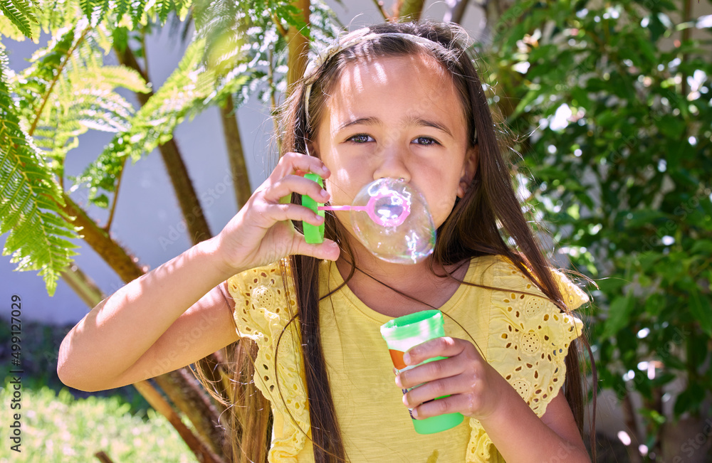 My bubbles brings all the fun to the yard. Shot of an adorable little girl blowing bubbles outside.