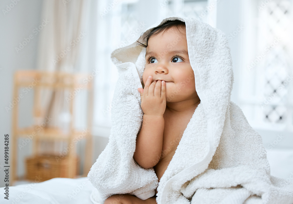 I taste so fresh. Shot of an adorable baby covered in a towel after bath time.