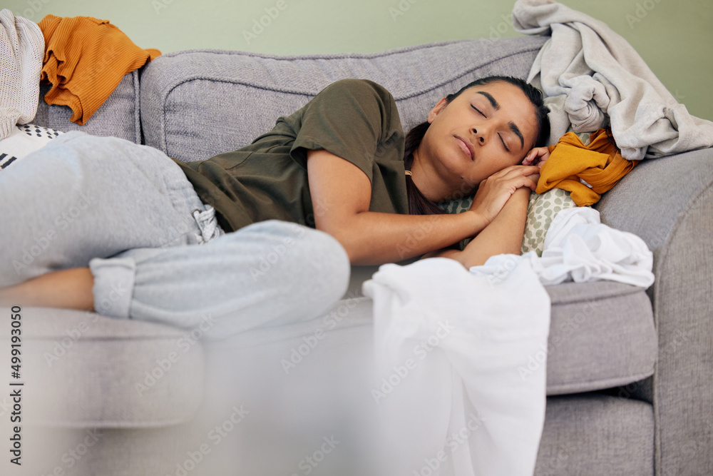 Sleep is way more fun than these chores. Shot of a young woman sleeping on the couch at home.