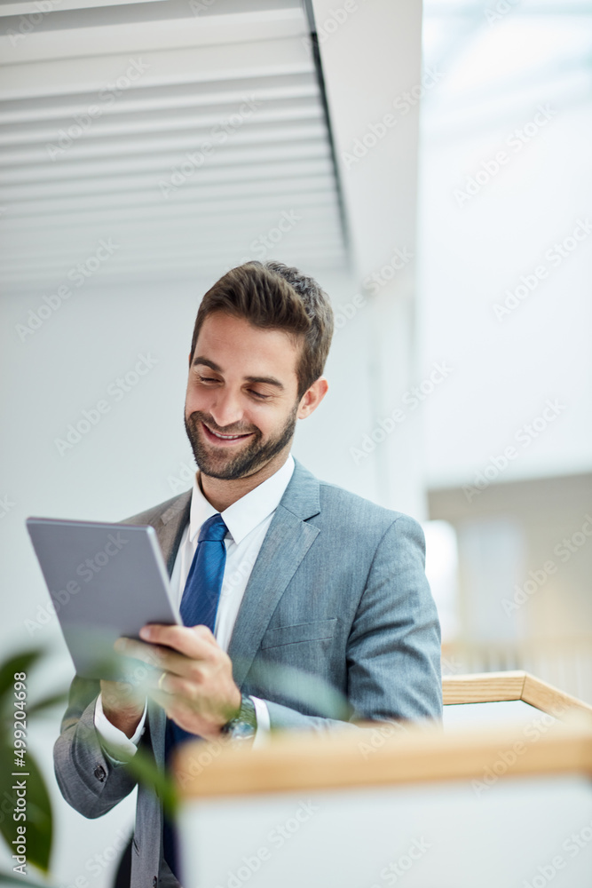 Staying in control of his success. Shot of a young businessman using a digital tablet in an office.