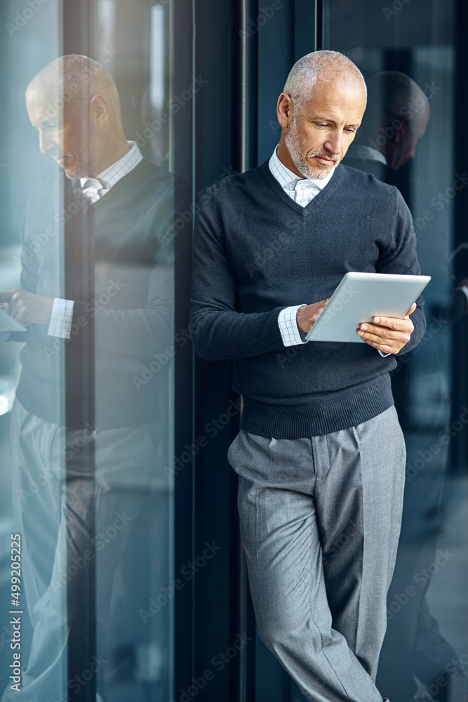 Technology brings a greater depth of knowledge. Shot of a mature businessman using his digital table