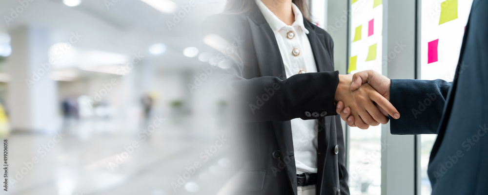 Business people handshake in corporate office in widen view showing professional agreement on a fina