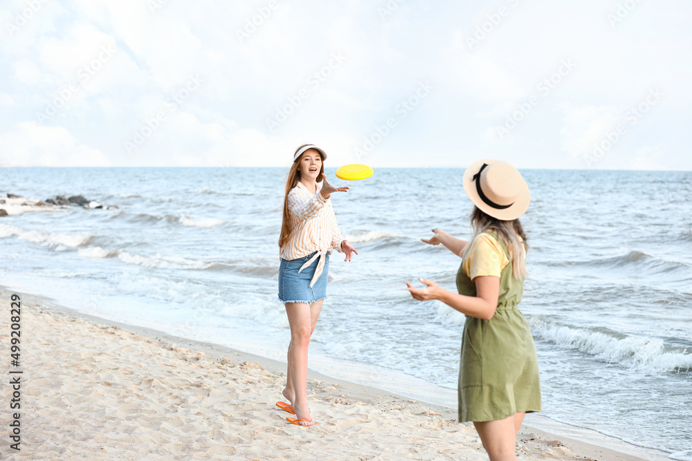 快乐的年轻女子在海边玩飞盘