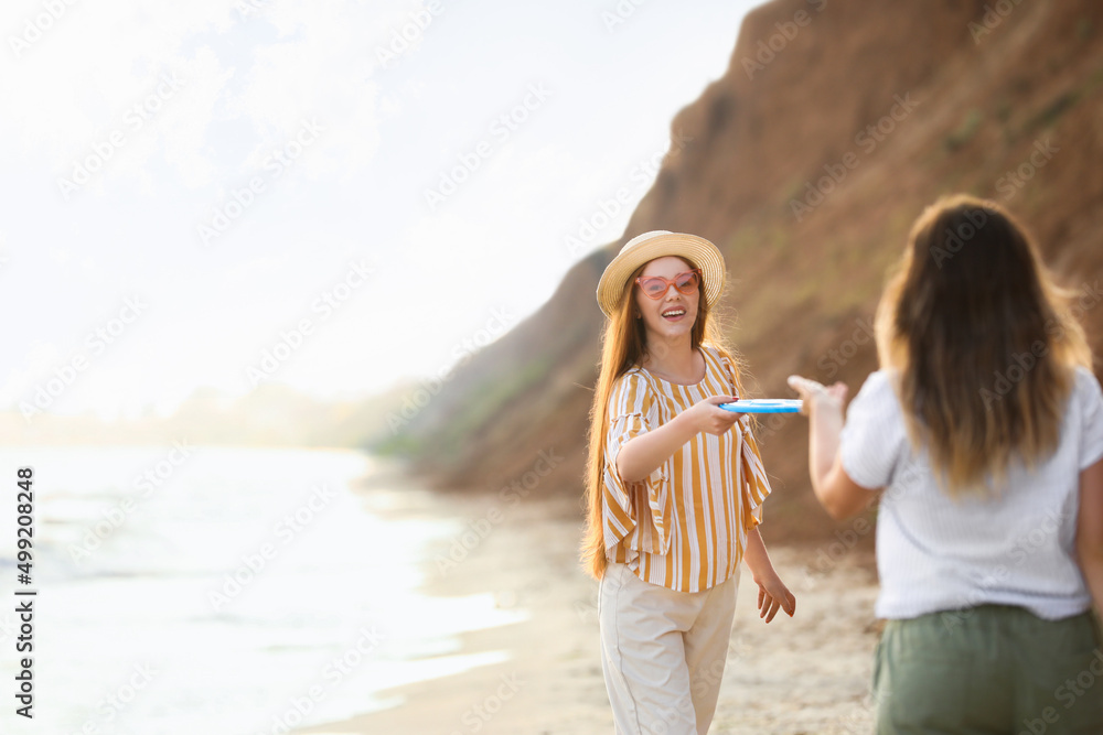 快乐的年轻女子在海边玩飞盘