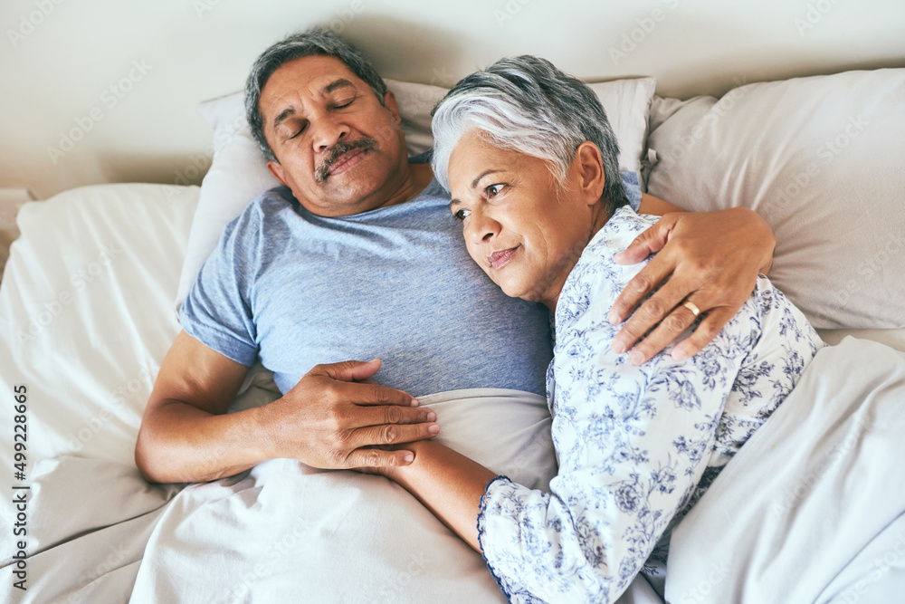 In love since the day we met. Shot of a relaxed mature couple lying in bed together at home in durin