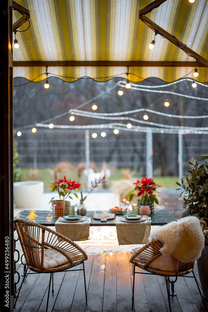 Cozy backyard with decorated and served table for a dinner. View from the opened window