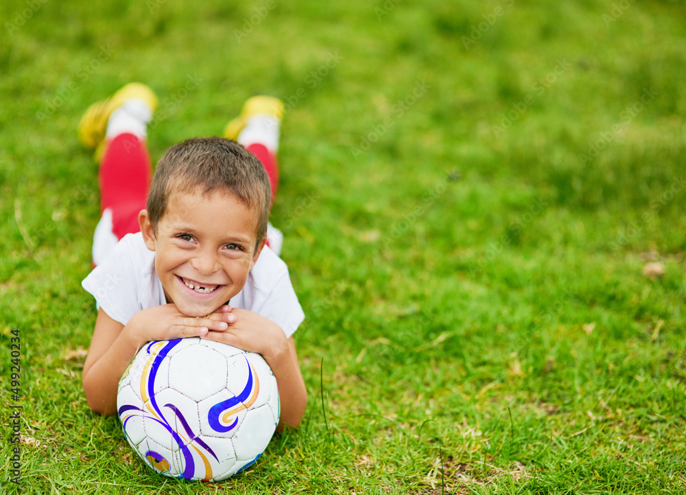 I love football. Portrait of a young boy playing soccer outside.