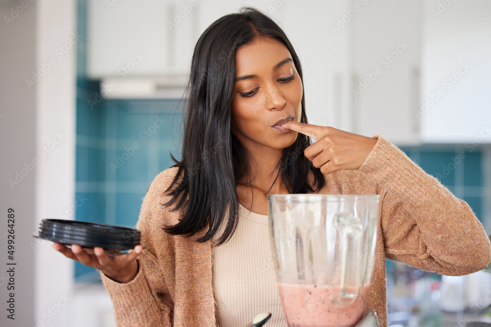 味道和看起来一样美味。一个年轻女人在家准备健康奶昔的镜头。