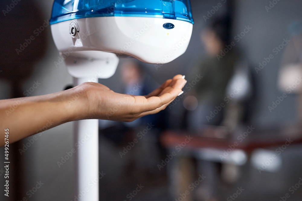 Before you start be safety smart. Shot of a businesswoman using a hand sanitising dispenser in a mod