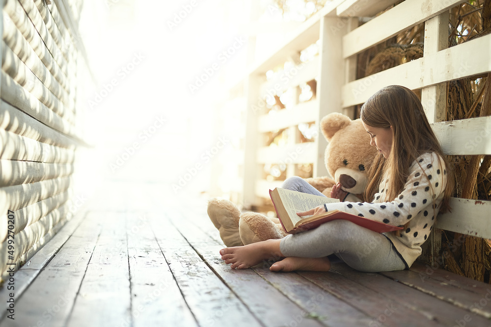 Which story should we ready next teddy. Shot of a little girl reading a book with her teddy bear bes