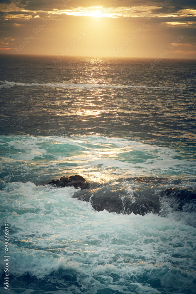 Follow the sea and make some waves. Shot of ocean waves crashing against boulders on the seashore.