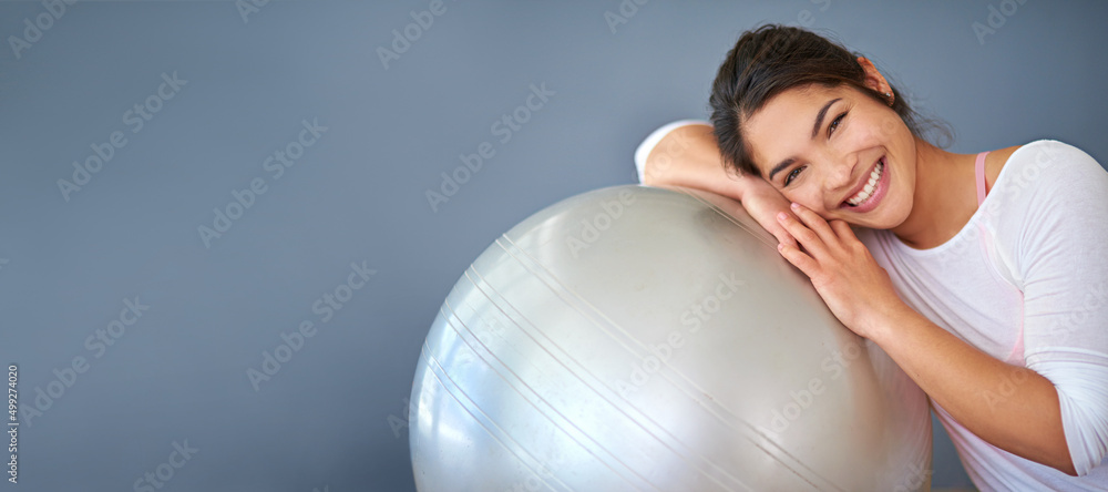 Exercising with my swiss ball makes me happy. Cropped shot of a sporty young woman leaning on a pila