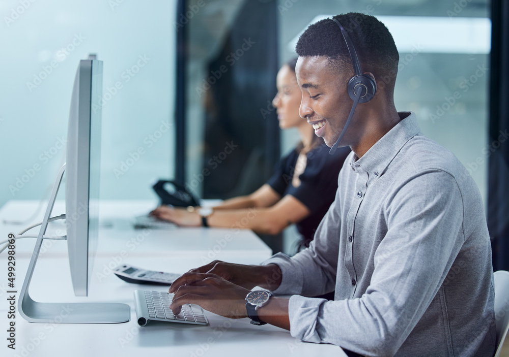 Im always happy to help. Shot of a young call centre agent typing in an office.