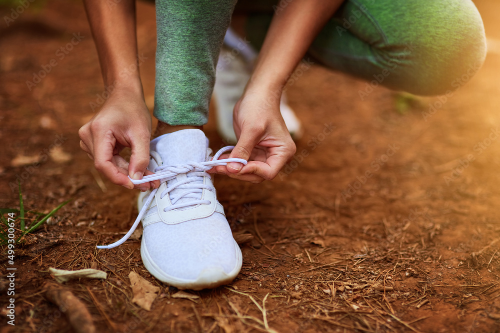 Make sure you wear something comfortable. Shot of a sporty young woman tying her shoelaces before a 