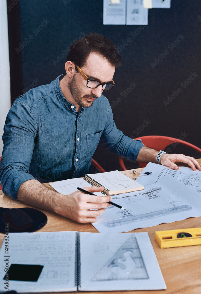 Creativity at work. Cropped shot of a handsome young male architect working with blueprints in a mod