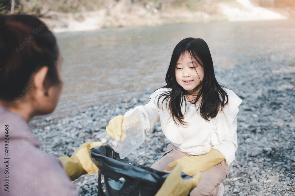 地球日概念，妇女和女儿用垃圾袋捡垃圾，在大自然中清理以回收