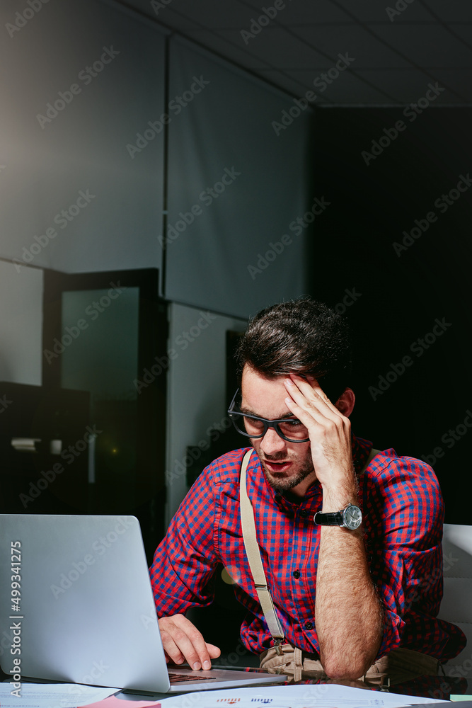 Struggling for ideas. Shot of a frustrated young designer looking stressed while working on his lapt