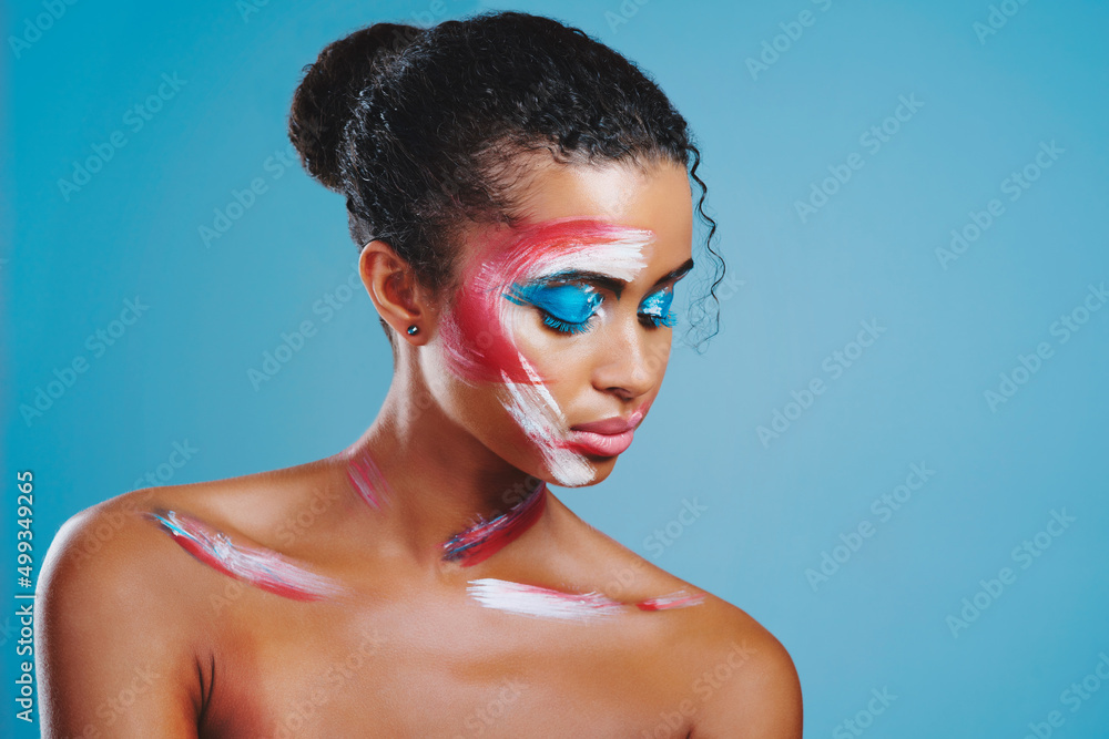 Face paint bring forth her true nature. Studio shot of a beautiful young woman covered in face paint