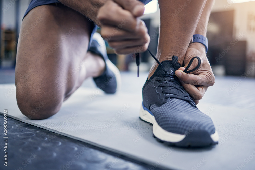 Lace up for a good workout. Closeup shot of an unrecognisable man tying his laces in a gym.