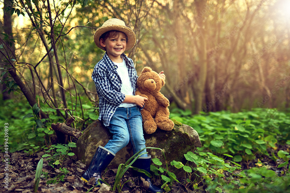 Theres no better companion in the woods. Shot of a little boy sitting in the forest with his teddy b