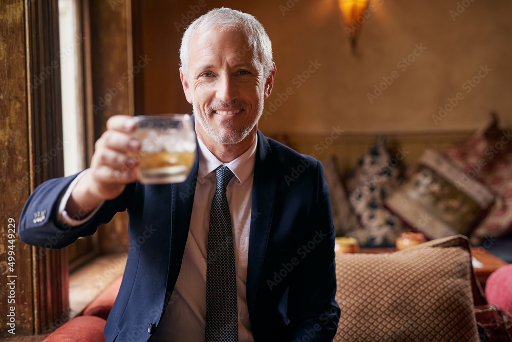 Raise a glass with me.... Portrait of a well-dressed mature man making a toast with a glass of whisk