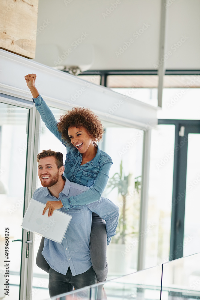 Heres to our success. Cropped shot of a young businessman piggybacking a colleague in an office.