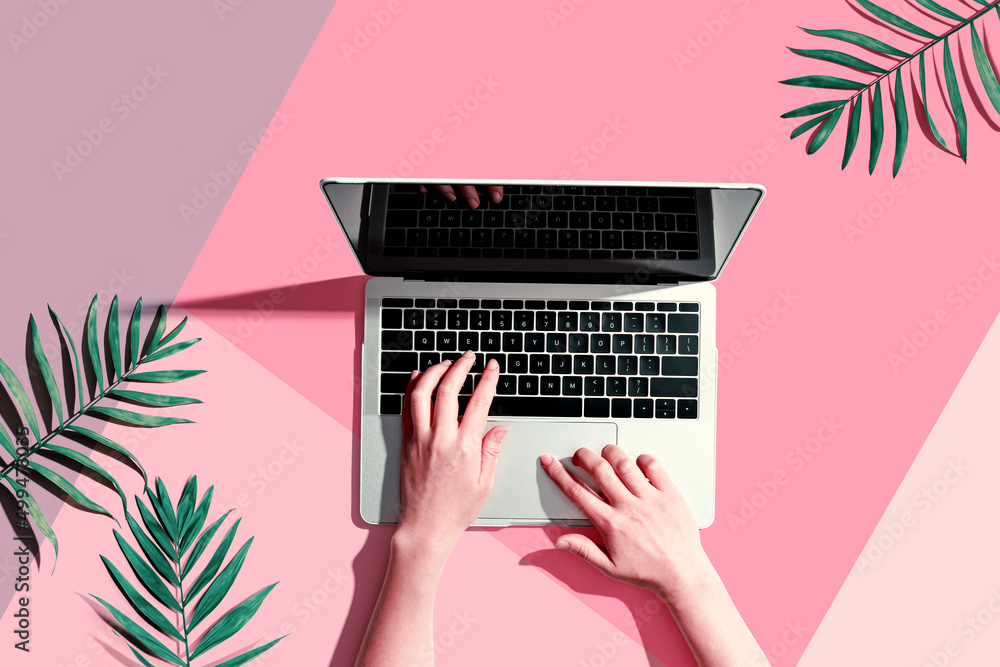 Person using a laptop computer with tropical leaves from above