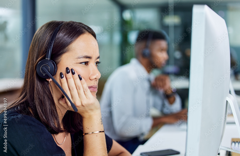 When does this day end. Shot of a young call centre agent looking confused while using a desktop pc 