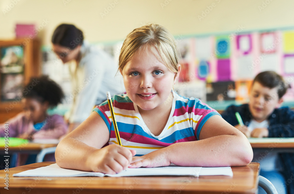 Im getting all my answers right. Shot of a young girl sitting in her classroom at school and writing