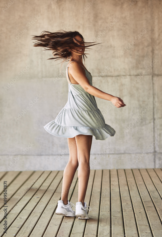 Give it a try, dive off a tree fall.into the sky. Shot of a young woman twirling in a dress against 