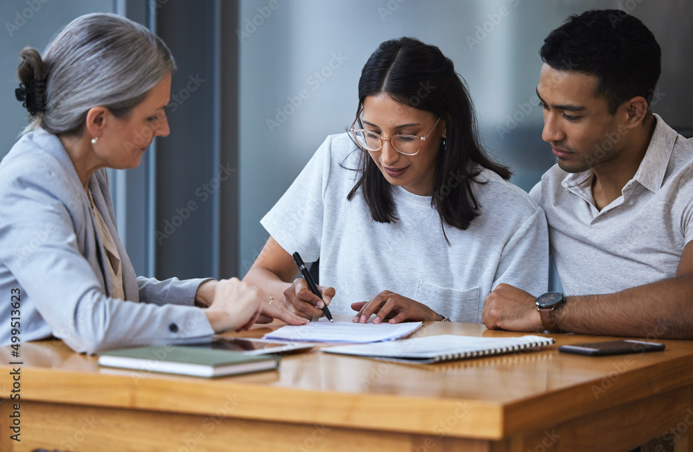 Signed yes on a promise to the future. Shot of a young couple meeting with a consultant to discuss p