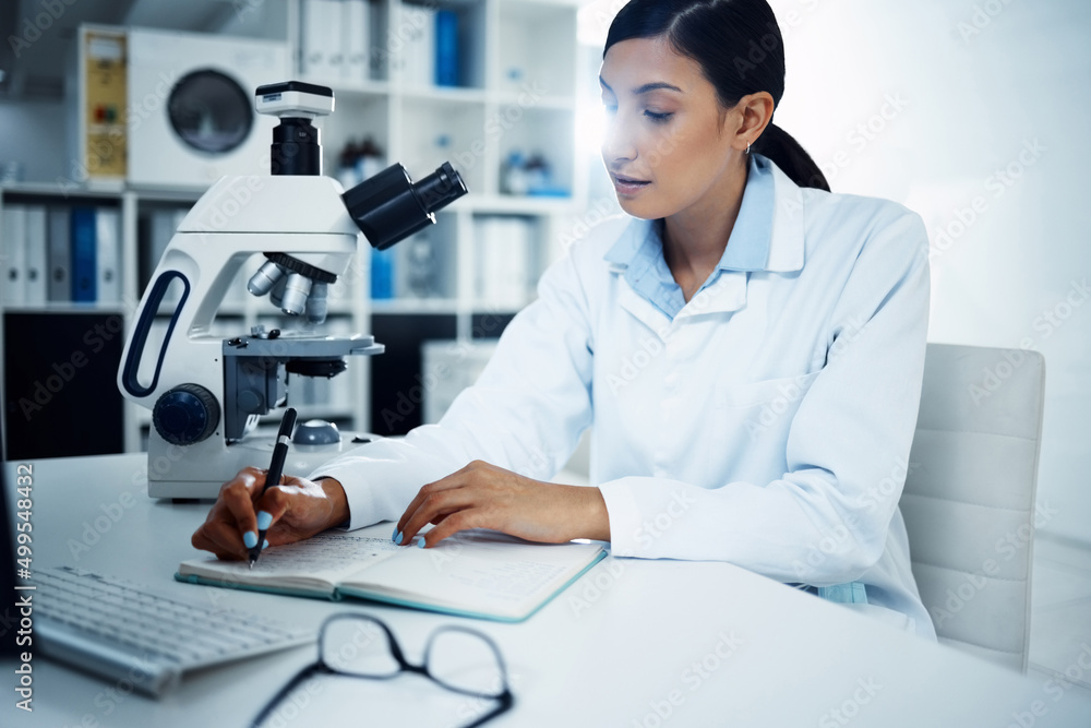 She studied hard, she got far. Shot of a young scientist writing notes while conducting medical rese