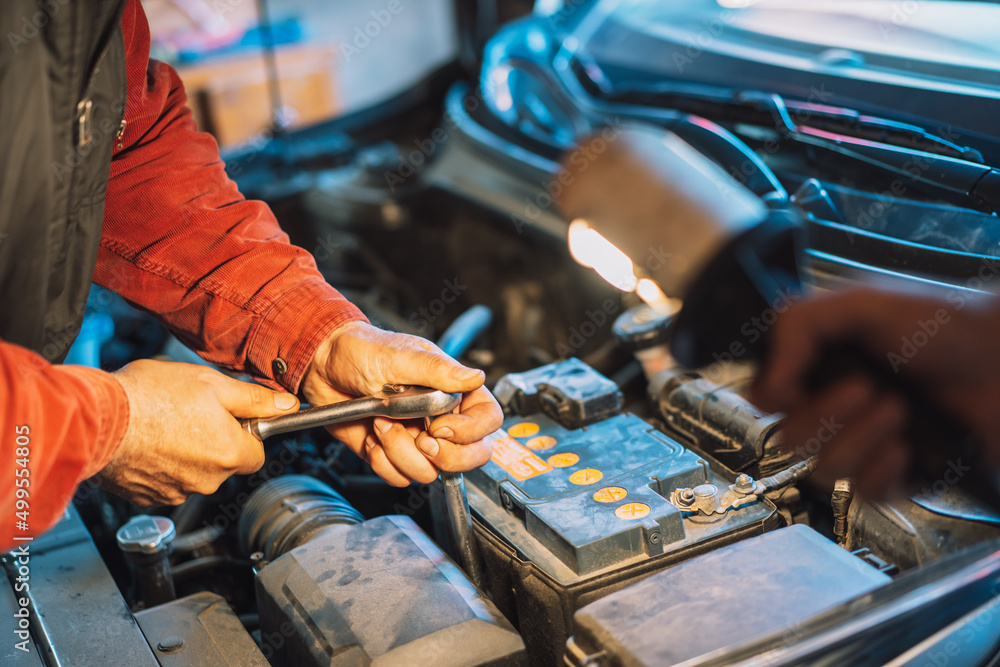 Mechanic screwing the battery with socket wrench.