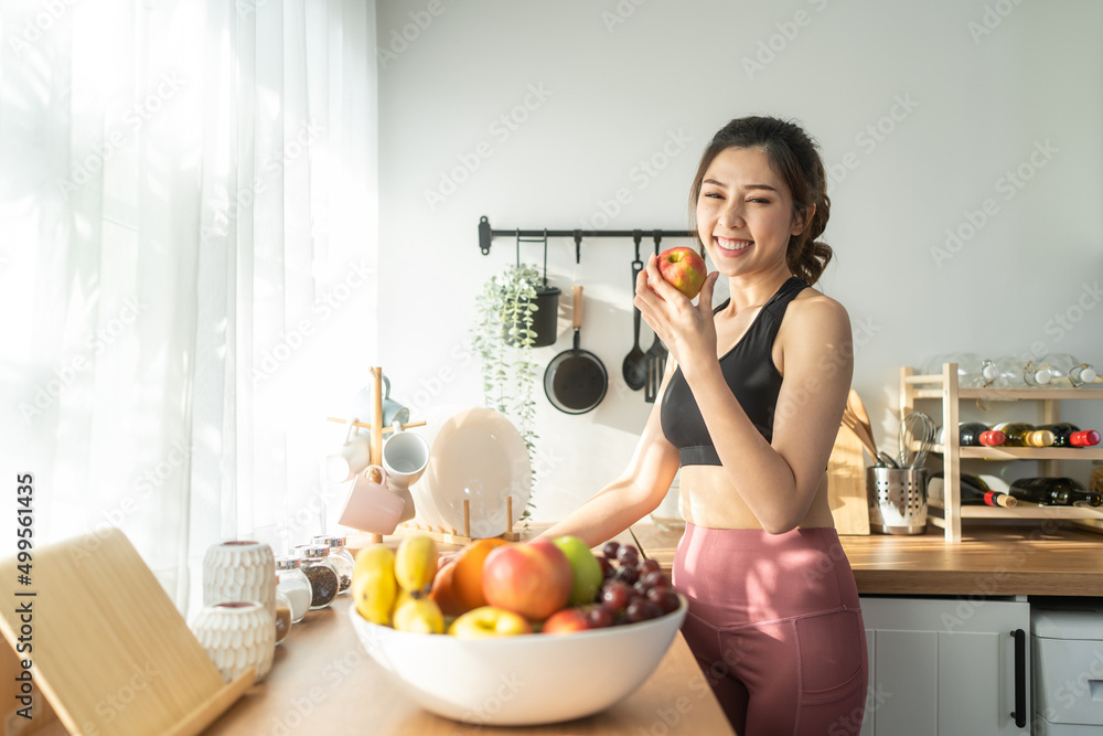 亚洲有魅力的活跃女性在家里的厨房里拿着一碗水果