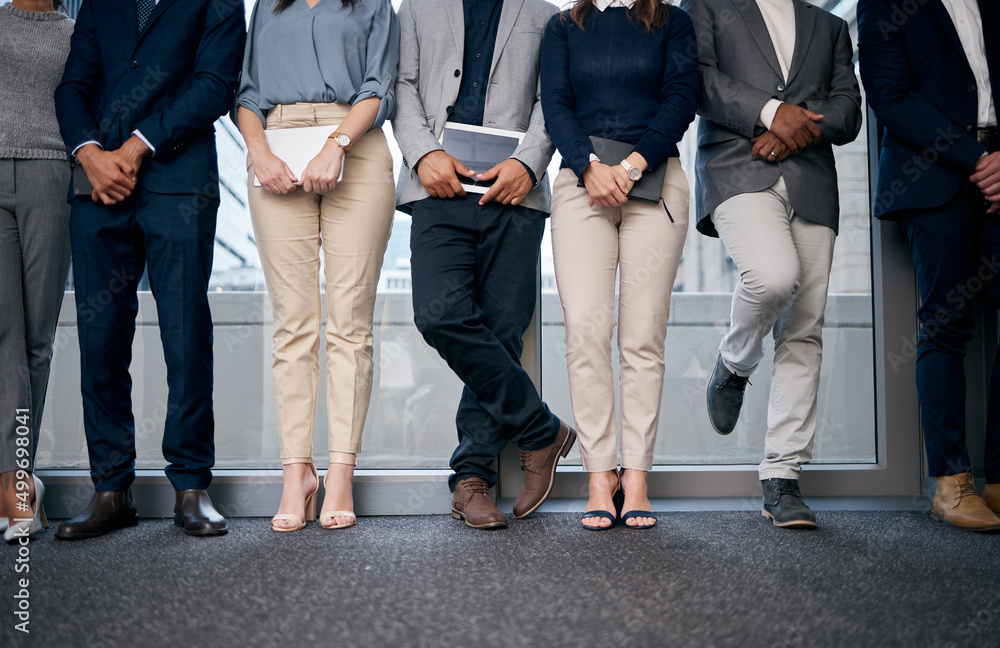 Patiently waiting for our turn. Shot of unrecognizable businesspeople standing in a row in a waiting