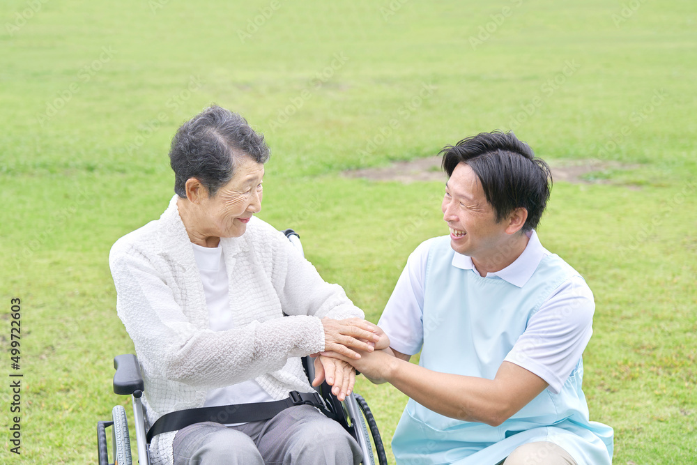 介護士と車椅子に乗った高齢者　屋外