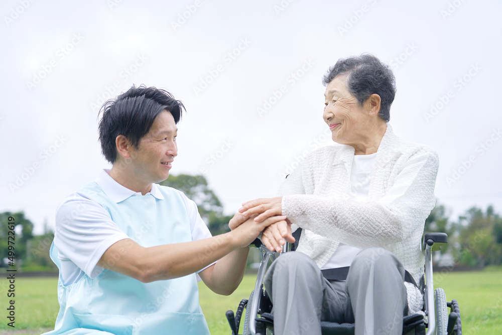 介護士と車椅子に乗った高齢者　屋外