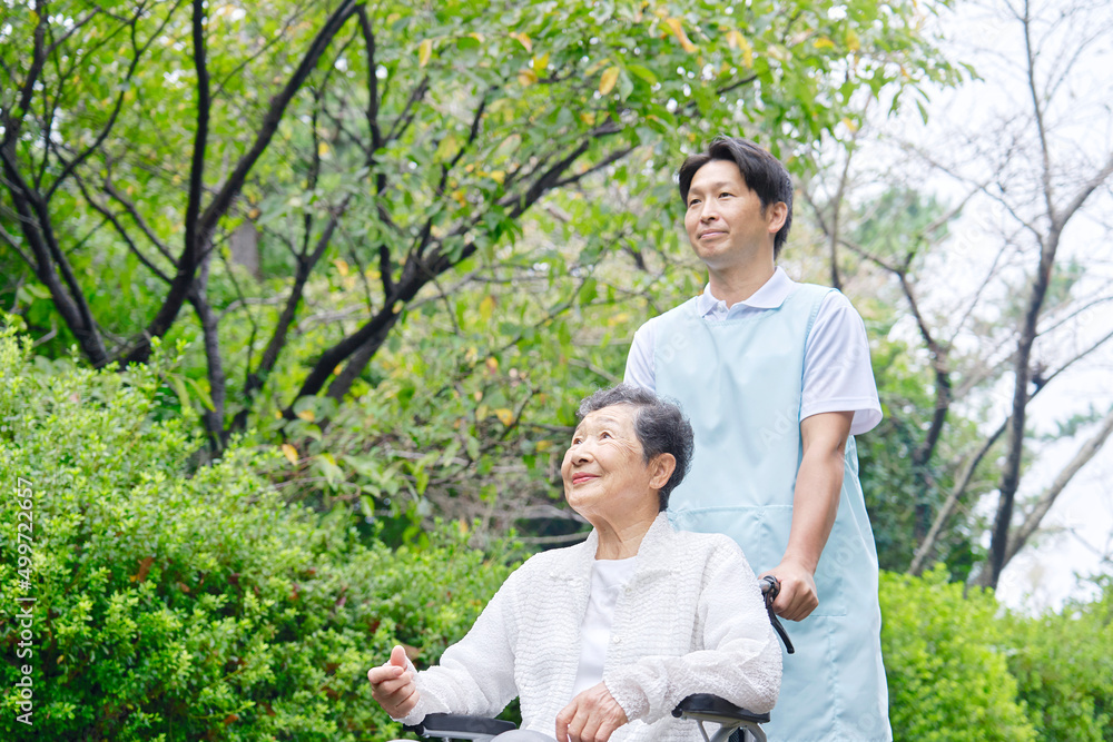 介護士と車椅子に乗った高齢者　屋外