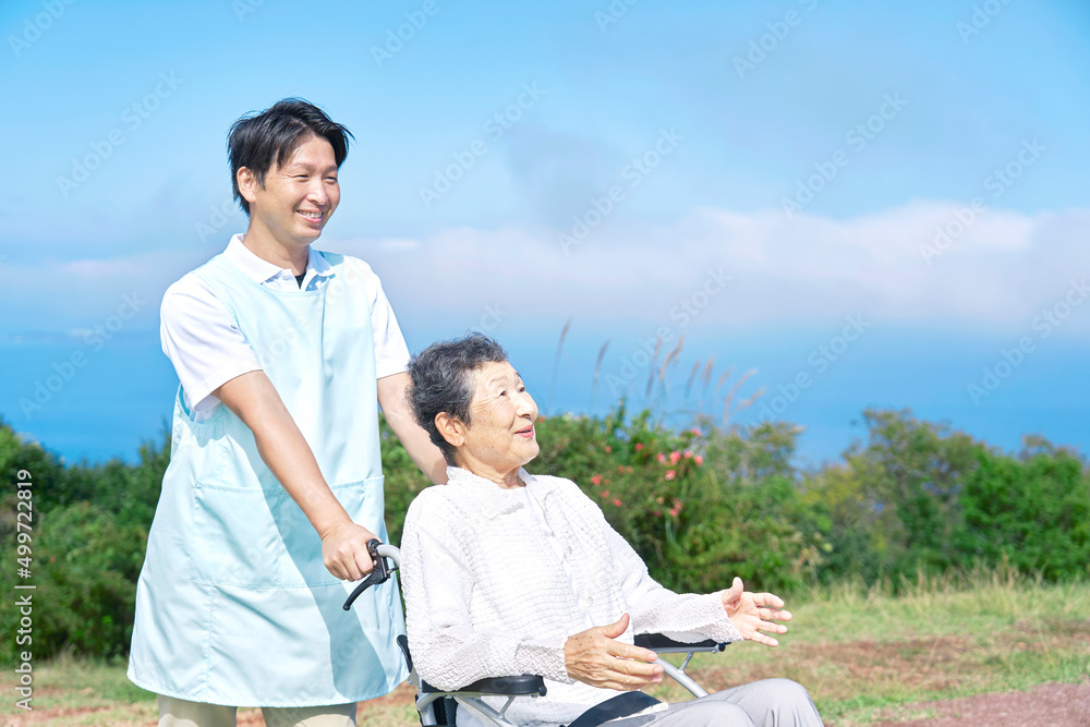 介護士と車椅子に乗った高齢者　屋外