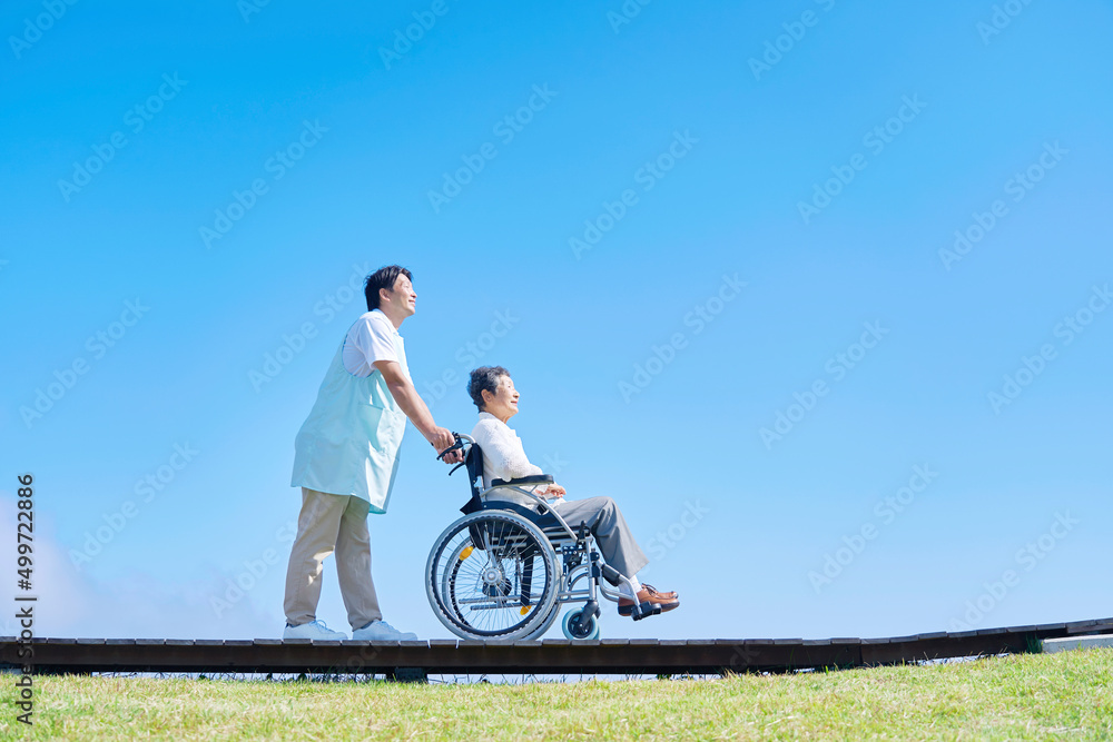 介護士と車椅子に乗った高齢者　屋外