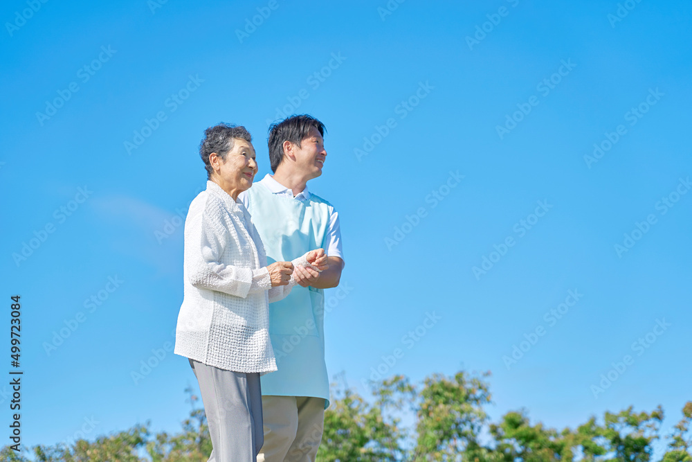 介護士と高齢者　屋外　散歩