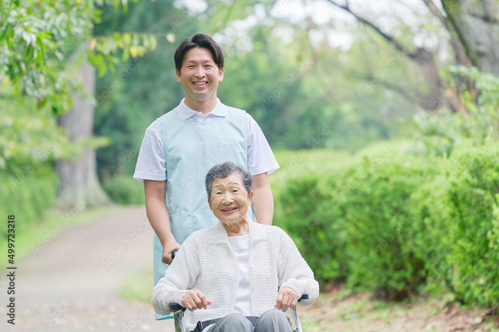 介護士と車椅子に乗った高齢者　屋外