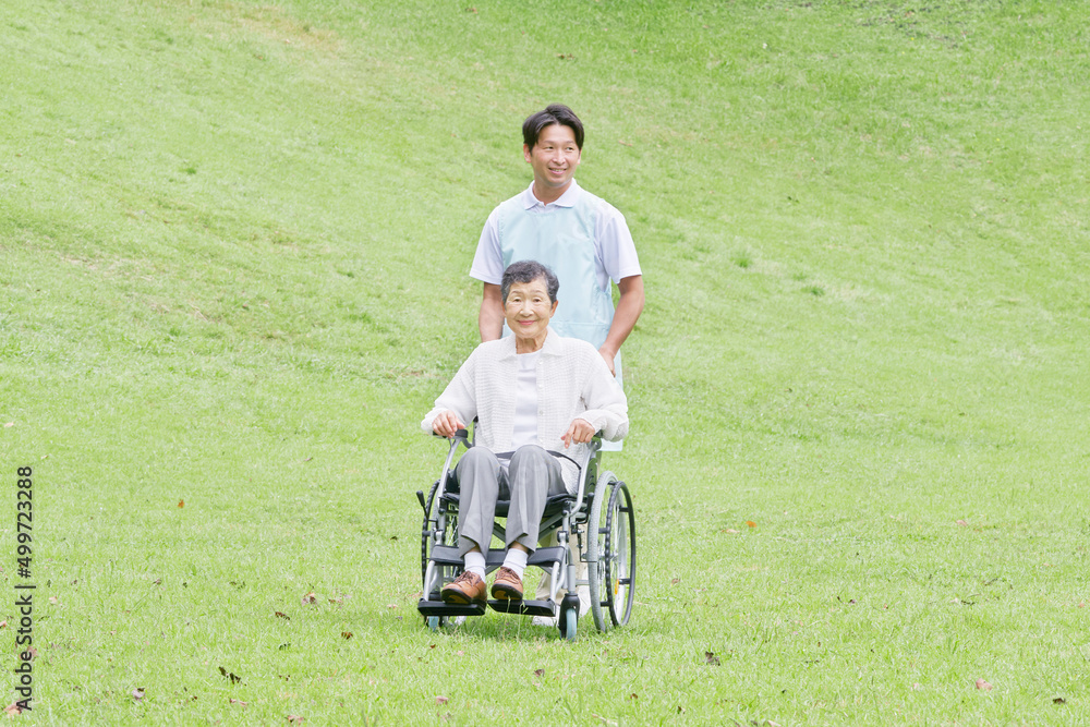 介護士と車椅子に乗った高齢者　屋外