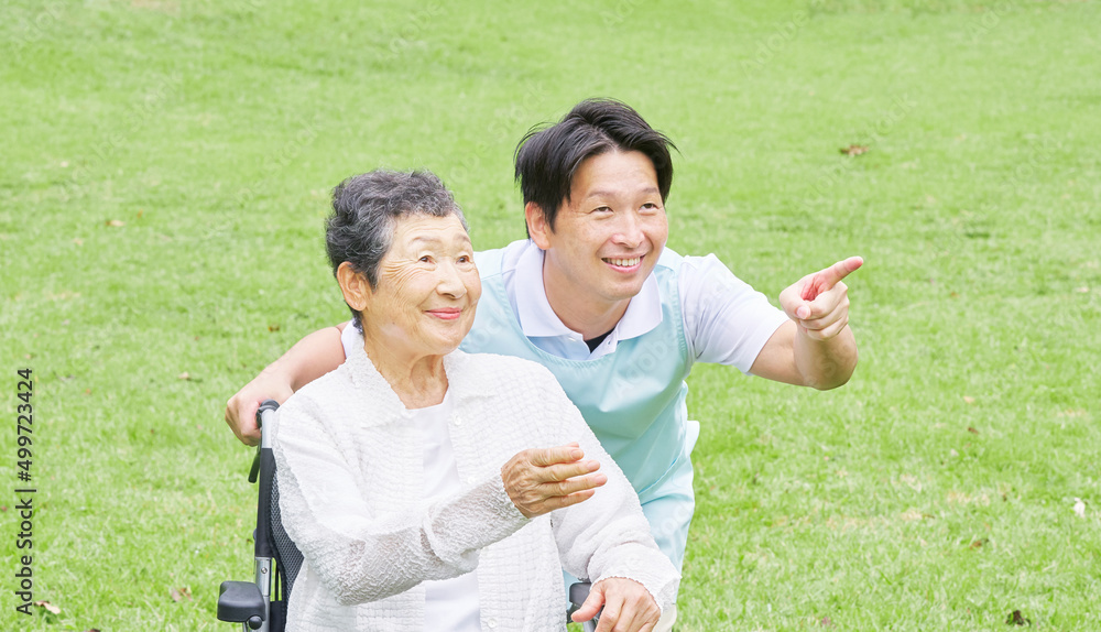 介護士と車椅子に乗った高齢者　屋外