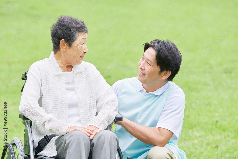 介護士と車椅子に乗った高齢者　屋外